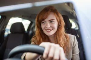 A woman smiling while driving a car
