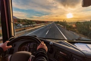 Image representing the view of a truck driver driving down a road at sunset