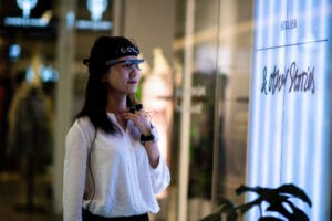 A woman wearing eye-tracking glasses and biosensors in a retail environment, analyzing visual attention and emotional responses to in-store displays.