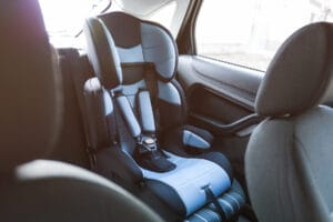 Rear-facing child safety seat installed in the back seat of a vehicle, highlighting proper installation and potential child presence when unattended.