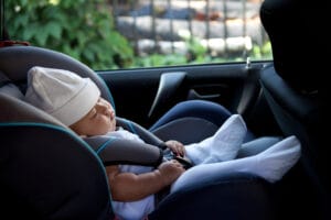 Newborn baby asleep in a rear-facing car seat, emphasizing the importance of child presence detection to prevent accidental entrapment.