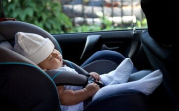 Newborn baby asleep in a rear-facing car seat, emphasizing the importance of child presence detection to prevent accidental entrapment.