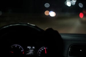 Driver holding steering wheel and driving on highway at night