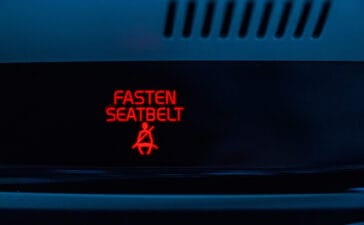 Close-up of illuminated “Fasten Seatbelt” dashboard warning in red—representing Euro NCAP’s stricter 2026 rules for visual and audible seatbelt reminders.
