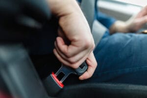 Person fastening a seatbelt in a vehicle, symbolizing proper seatbelt use and the focus of Euro NCAP’s updated 2026 requirements for misuse detection and rear-seat compliance.