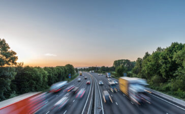 Highway traffic at sunset representing EU road safety and upcoming GSR requirements for DDAW and ADDW driver attention systems.