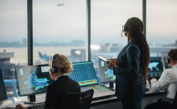Air traffic control operators training in a simulator, monitoring radar displays and flight data to assess situational awareness and decision-making under workload.