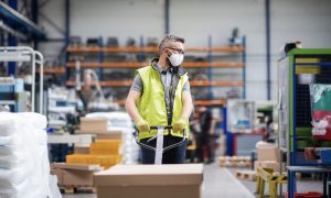 Worker with protective mask working in industrial factory or warehouse