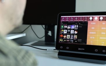 A person using eye tracking to browse music playlists on a Smartbox Grid Pad.