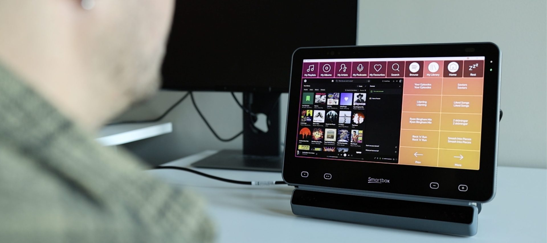 A person using eye tracking to browse music playlists on a Smartbox Grid Pad.